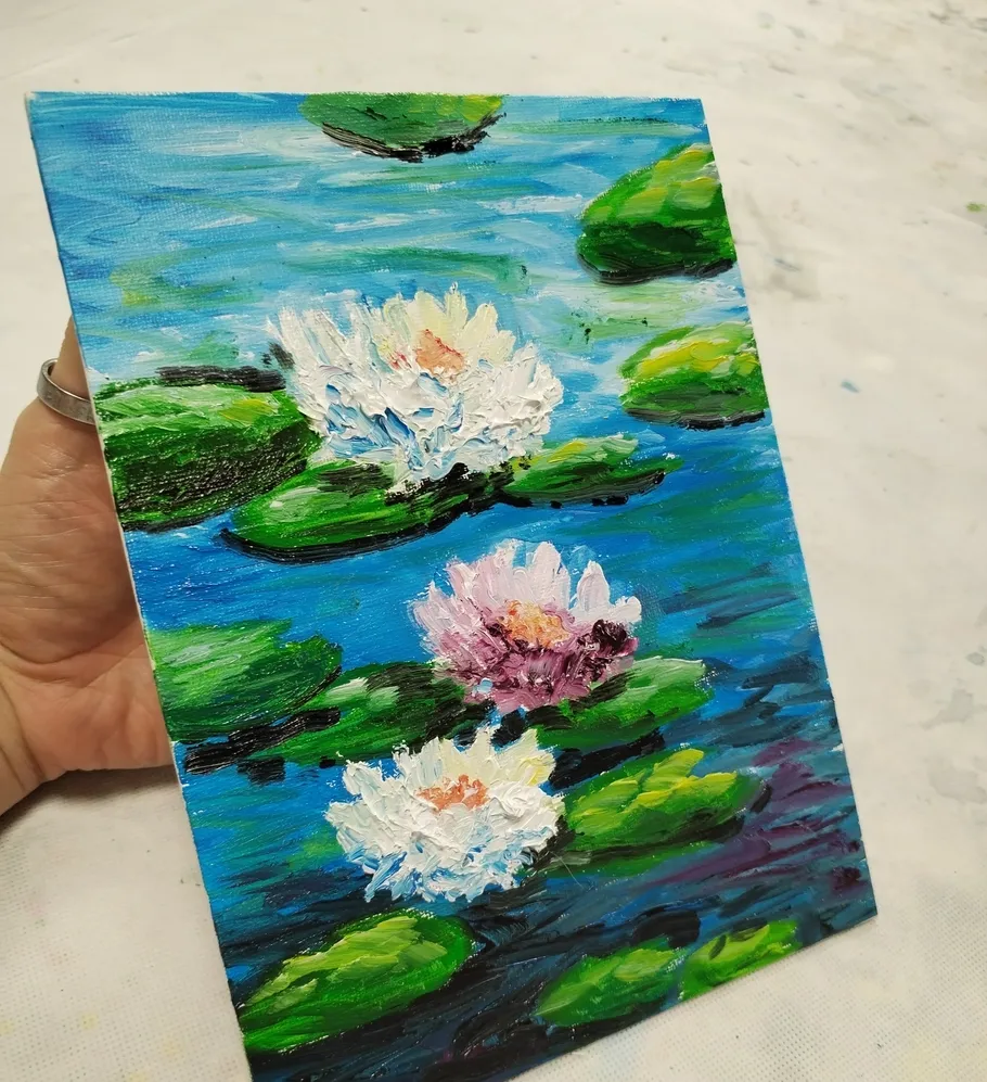 Hand holding painting of water lilies.