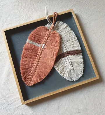 Two macramé leaves in a wooden tray.