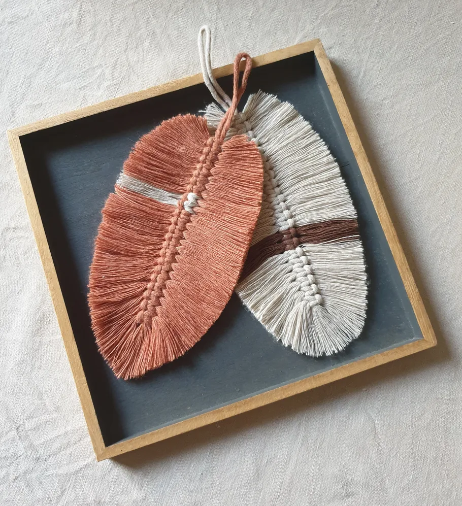 Two macramé leaves in a wooden tray.