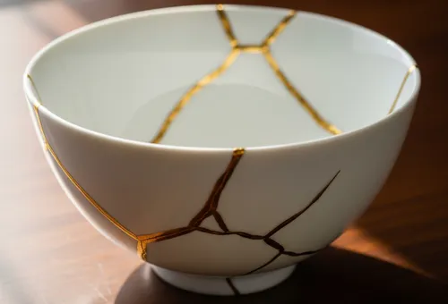 Ceramic bowl repaired with gold lines on table.