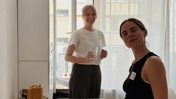 Two women smiling in a bright kitchen.