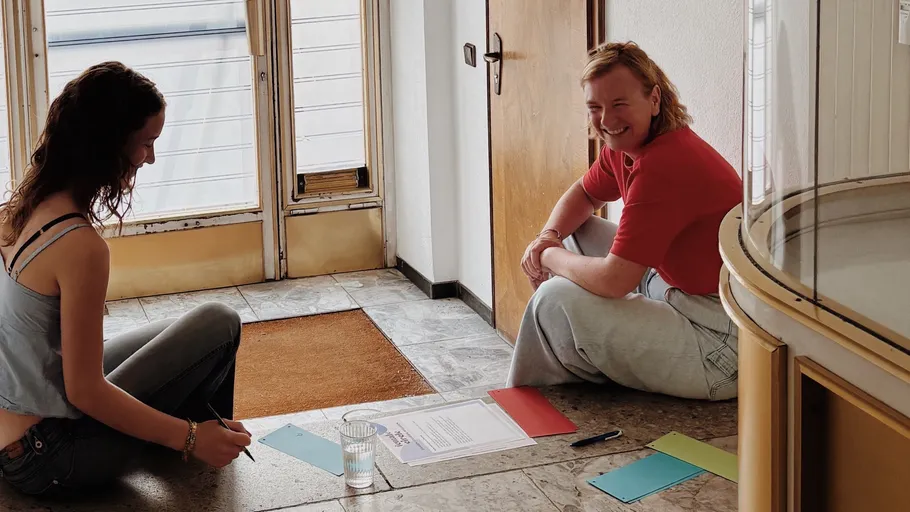Two people sitting on tiled floor, talking.