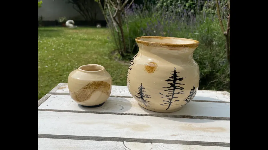Two ceramic vases on outdoor table.
