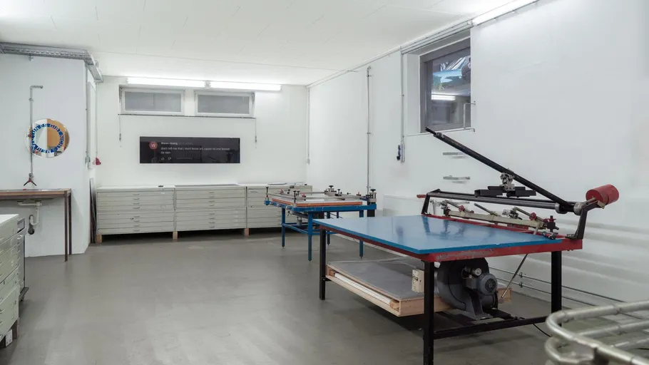 Leeres Druckstudio mit Arbeitstischen und Geräten.