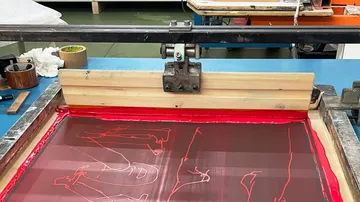 Screen printing setup with red ink in workshop.