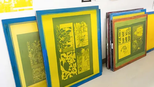 Bunte Siebdrucke lehnen an einer Wand.