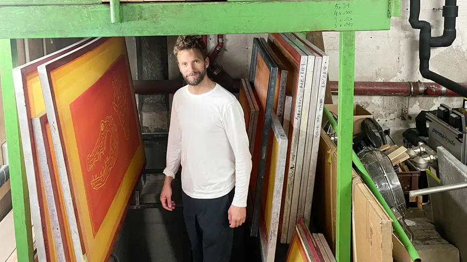 Man standing among stacked screen frames.
