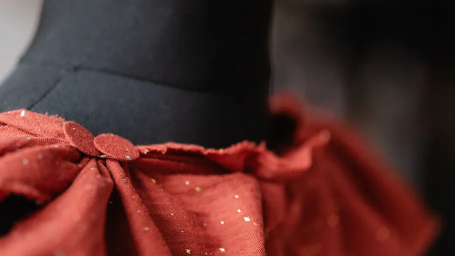 Red fabric draped on black mannequin neck.