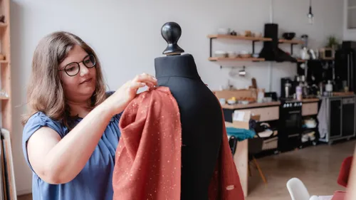 Frau passt Stoff an Schneiderpuppe im Studio an.