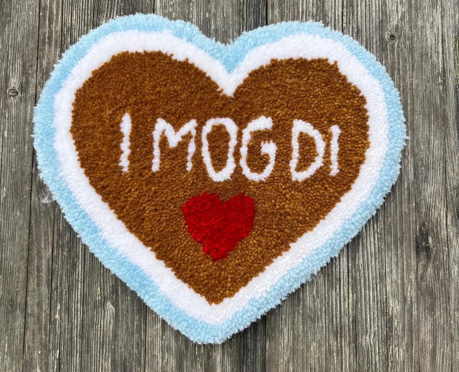 Heart-shaped rug with text on wooden background.