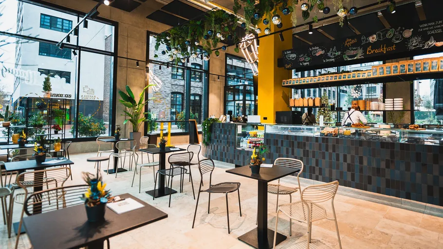 Modernes Café mit Sitzgelegenheiten und lebendiger Dekoration.