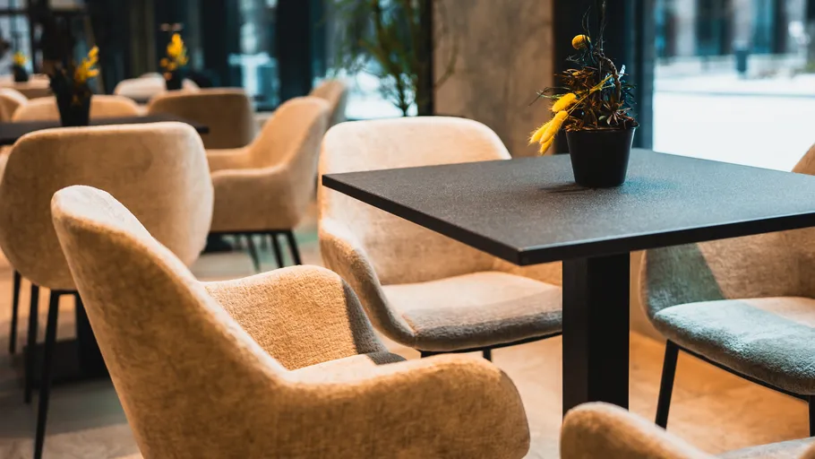 Modernes Café mit beigen Stühlen, schwarzem Tisch.