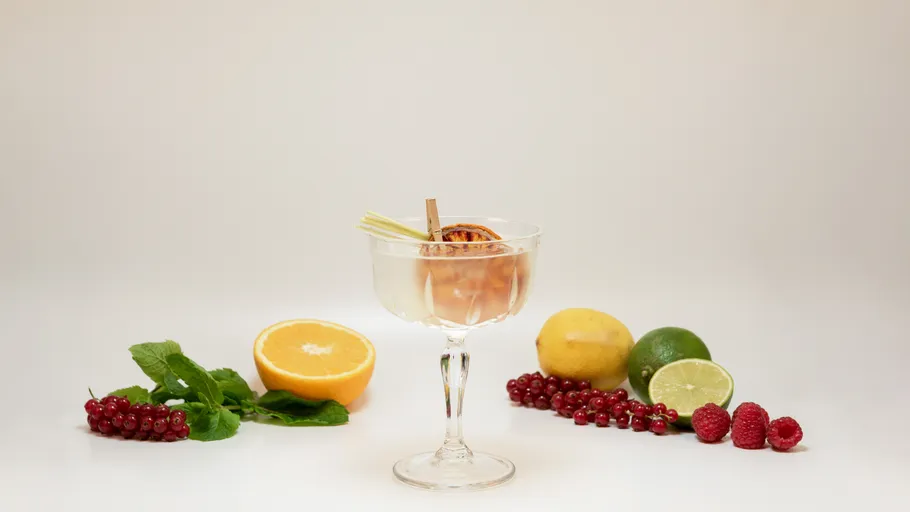 Cocktail glass with garnish, surrounded by fruits.