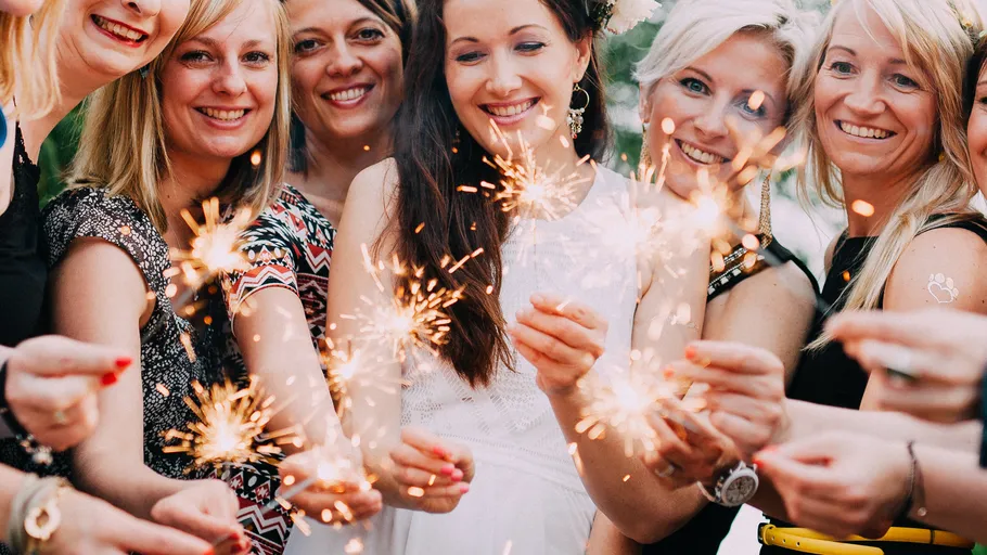 Frauen halten Wunderkerzen zur Feier, im Freien.