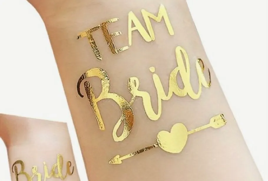 Goldenes Tattoo auf Haut mit 'Team Bride'.