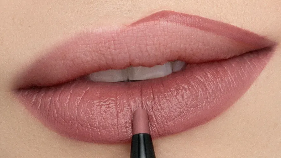 Lips being outlined with lip liner pencil.