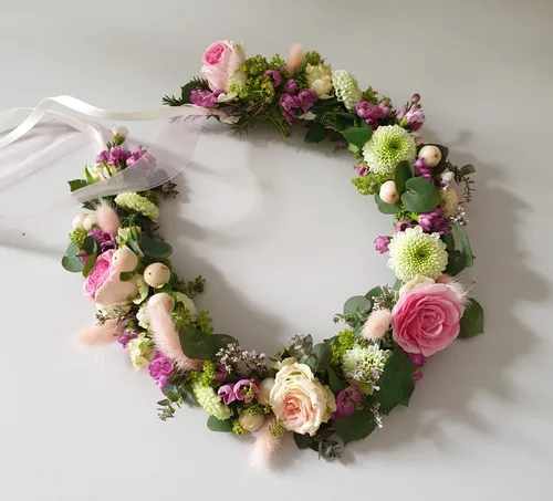 Blumenkranz mit rosa Rosen auf Tisch.