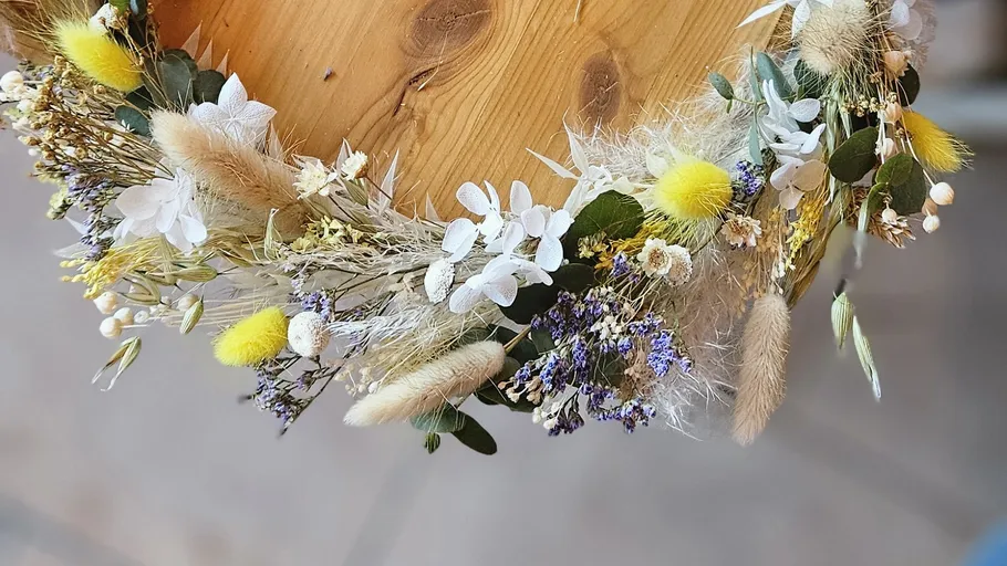 Floral wreath with diverse flowers on wood table.