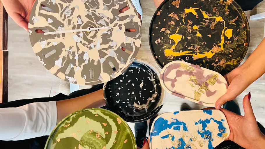 Hands holding colorful resin art pieces.