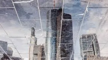 Buildings reflected in shattered glass surface.