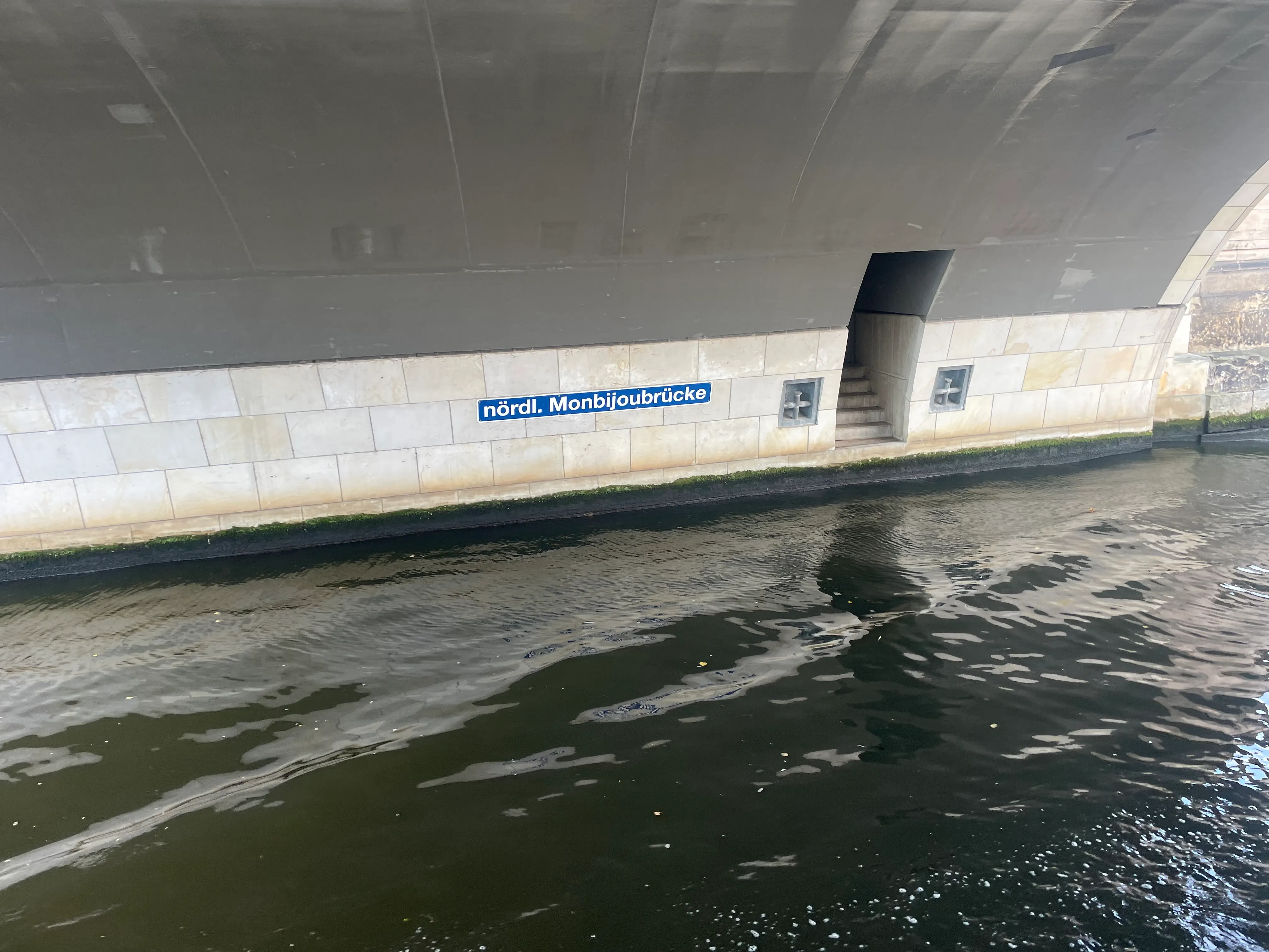 Bridge sign reading "nördl. Monbijoubrücke" above water.