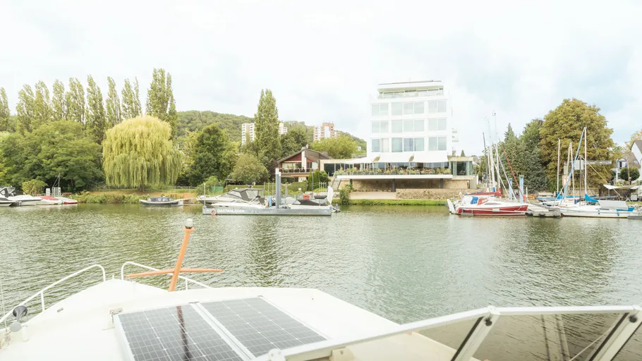 Flussblick mit Booten und modernem Gebäude.