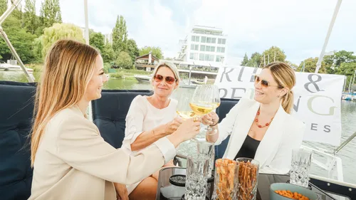 Three women toasting on a yacht outdoors.