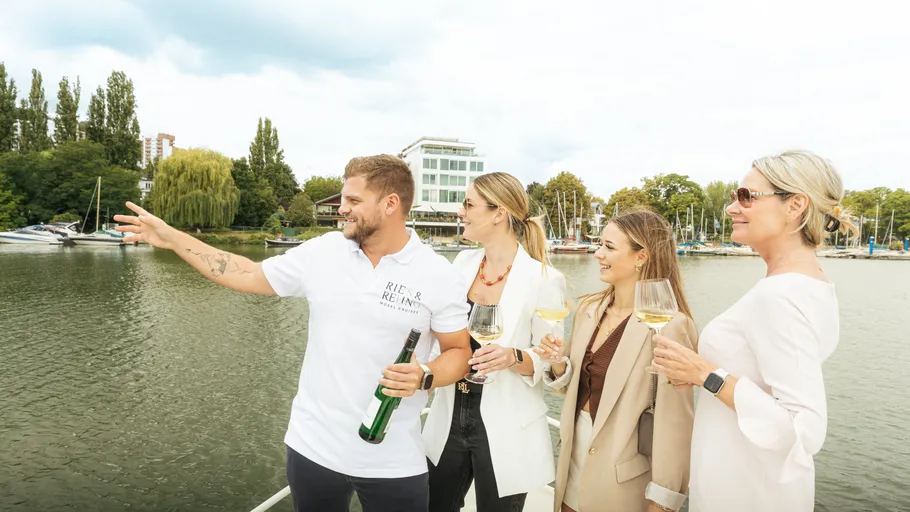 Gruppe stößt mit Wein auf einem Boot an.