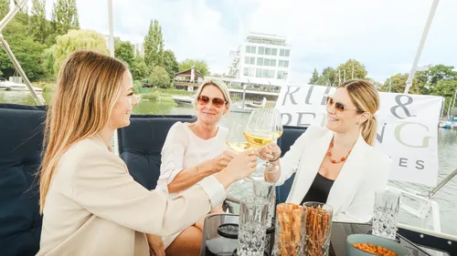 Three women clinking glasses on a boat.