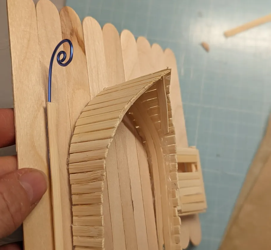 Holz-Bastelei mit gebogenem Draht, handgehalten.