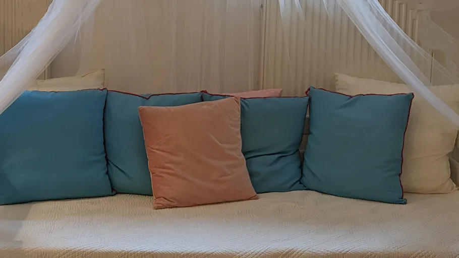 Blaue und rosa Kissen auf einem Bett.