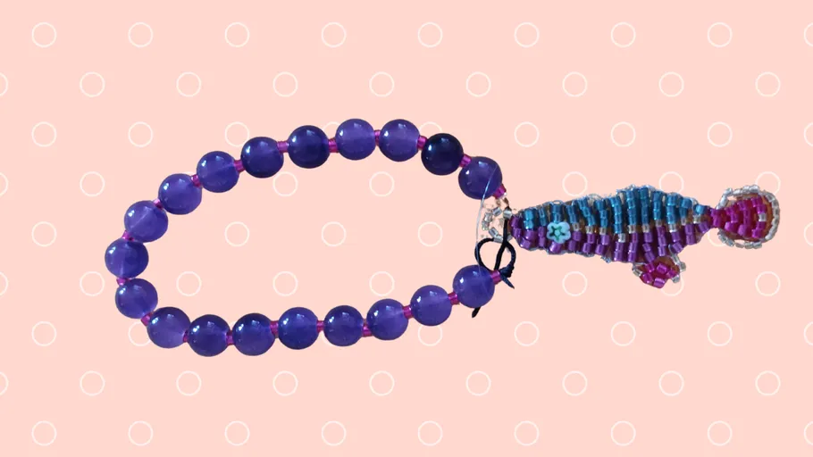Purple beaded bracelet with fish charm on dots.