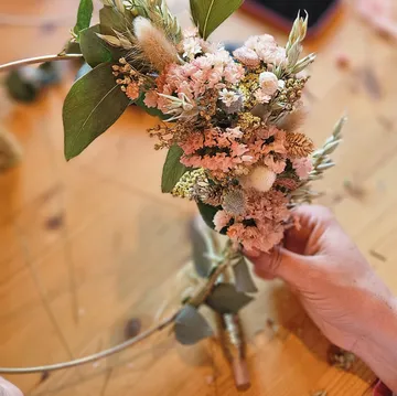 Hands arranging flowers on wooden table.