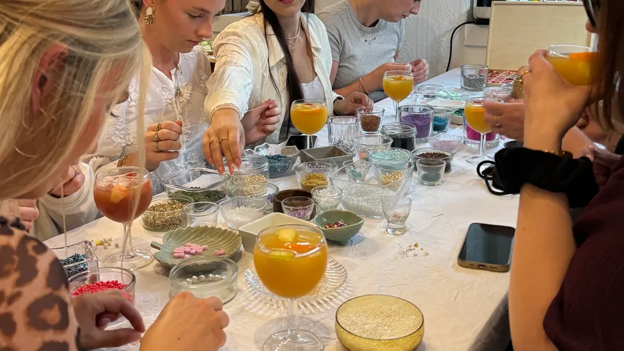 People crafting with beads, enjoying drinks.