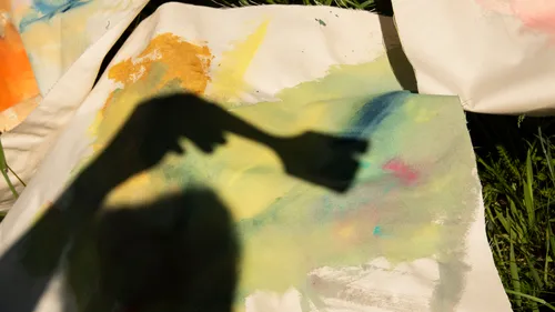 Schatten einer Hand malt auf bunte Leinwand draußen.