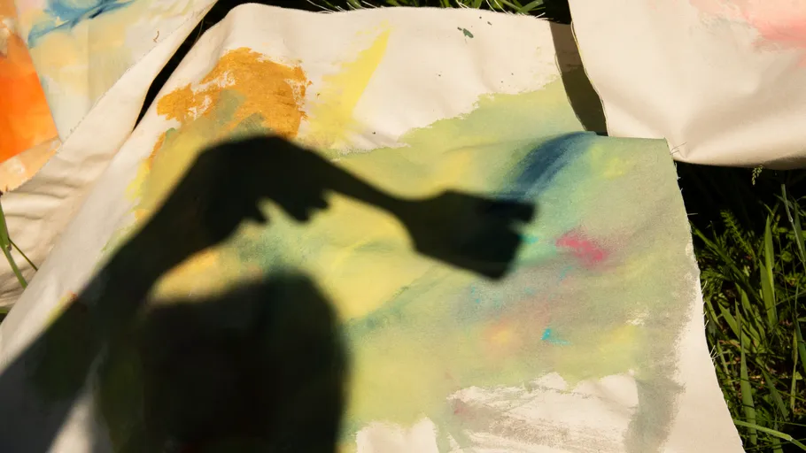 Schatten einer Hand malt auf bunte Leinwand draußen.