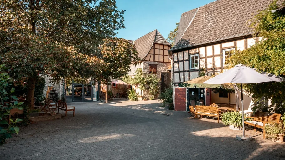 Hof mit Fachwerkhäusern und Bäumen.