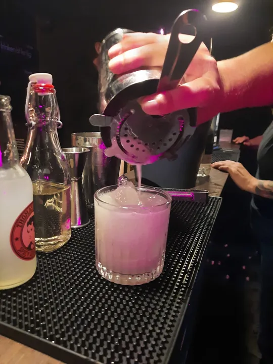 Barkeeper gießt Cocktail in ein Glas an der Bar.