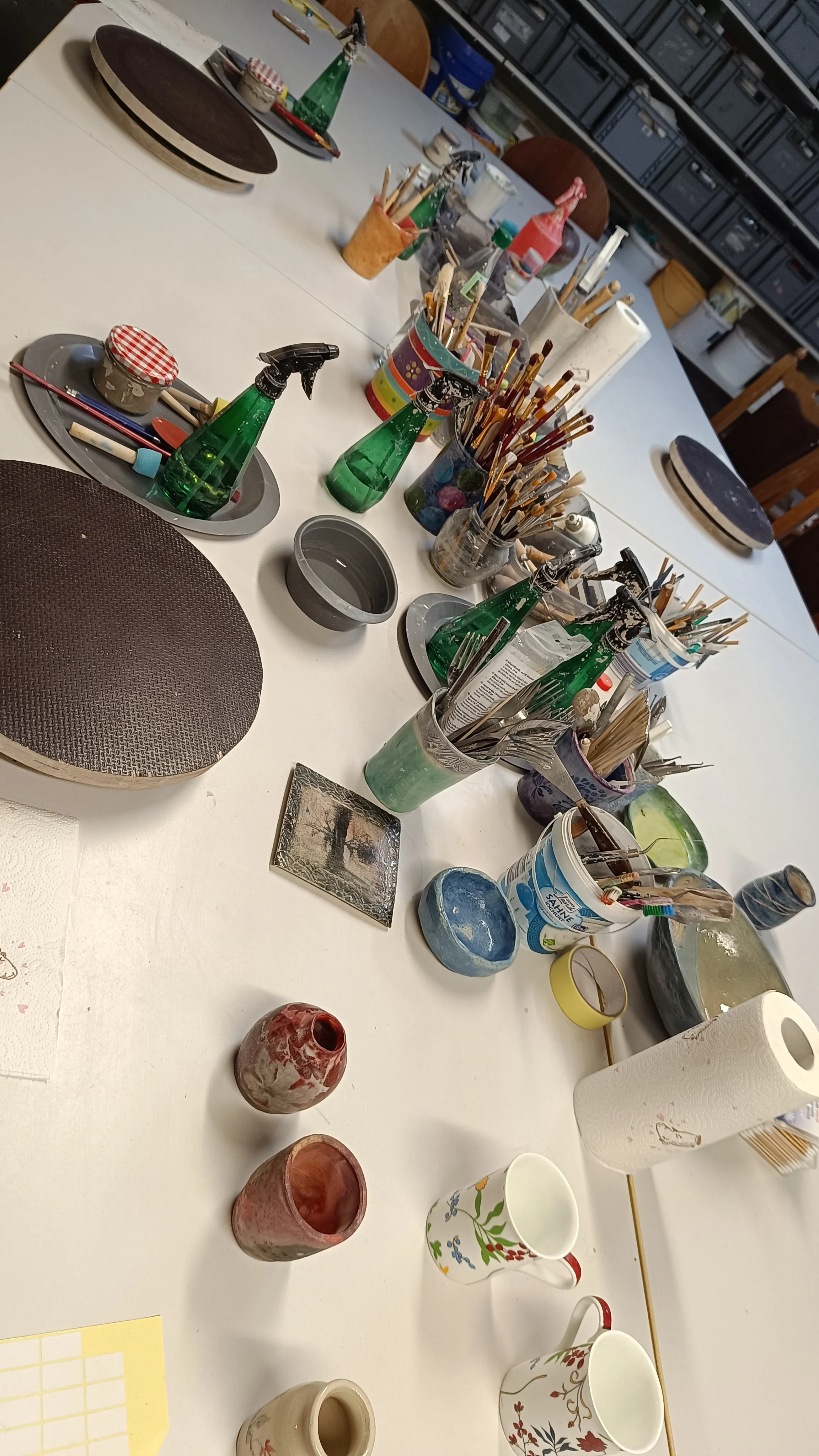 Art supplies and mugs on a table.