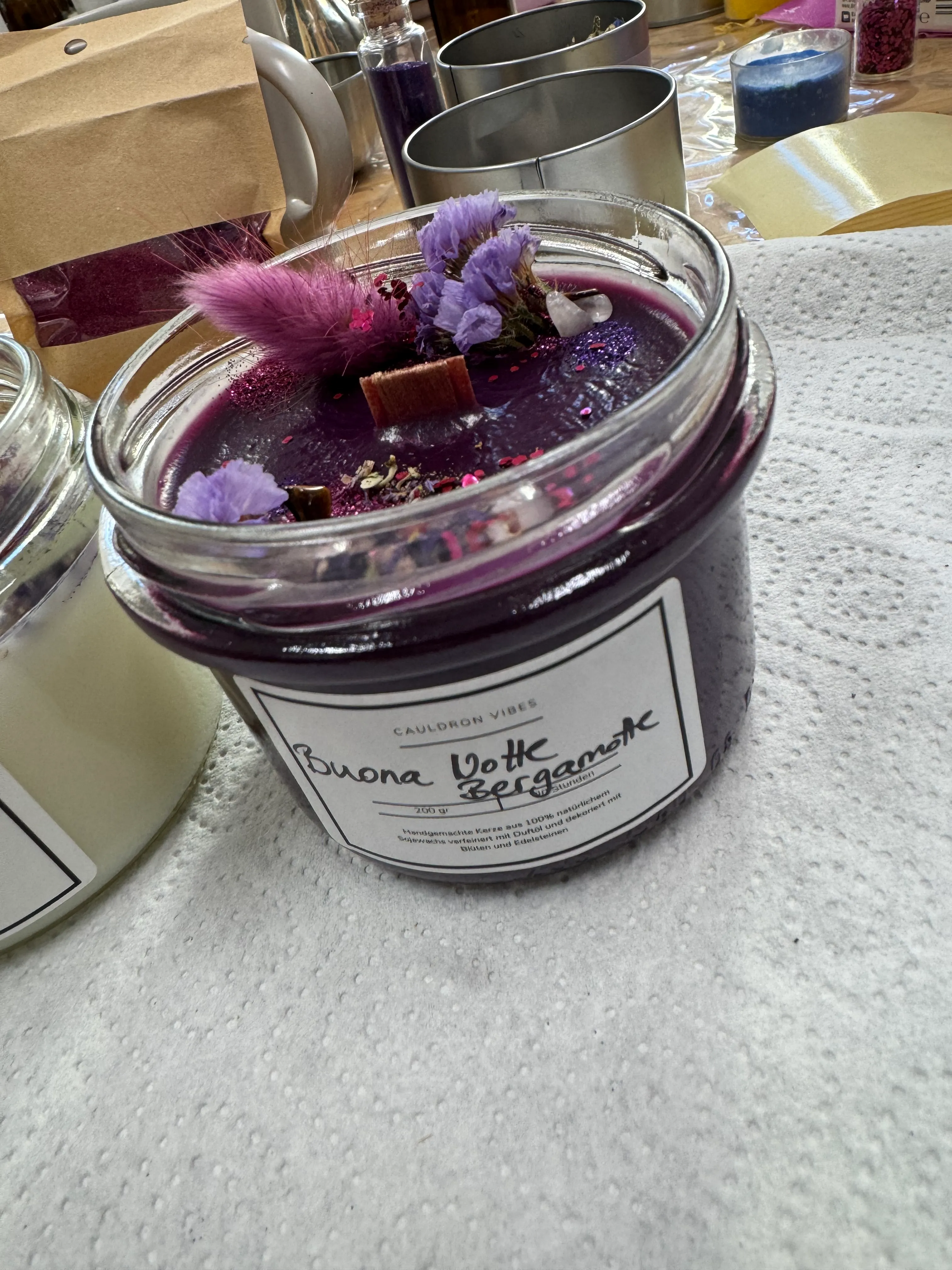 Lila Kerze mit getrockneten Blumen auf Tisch.