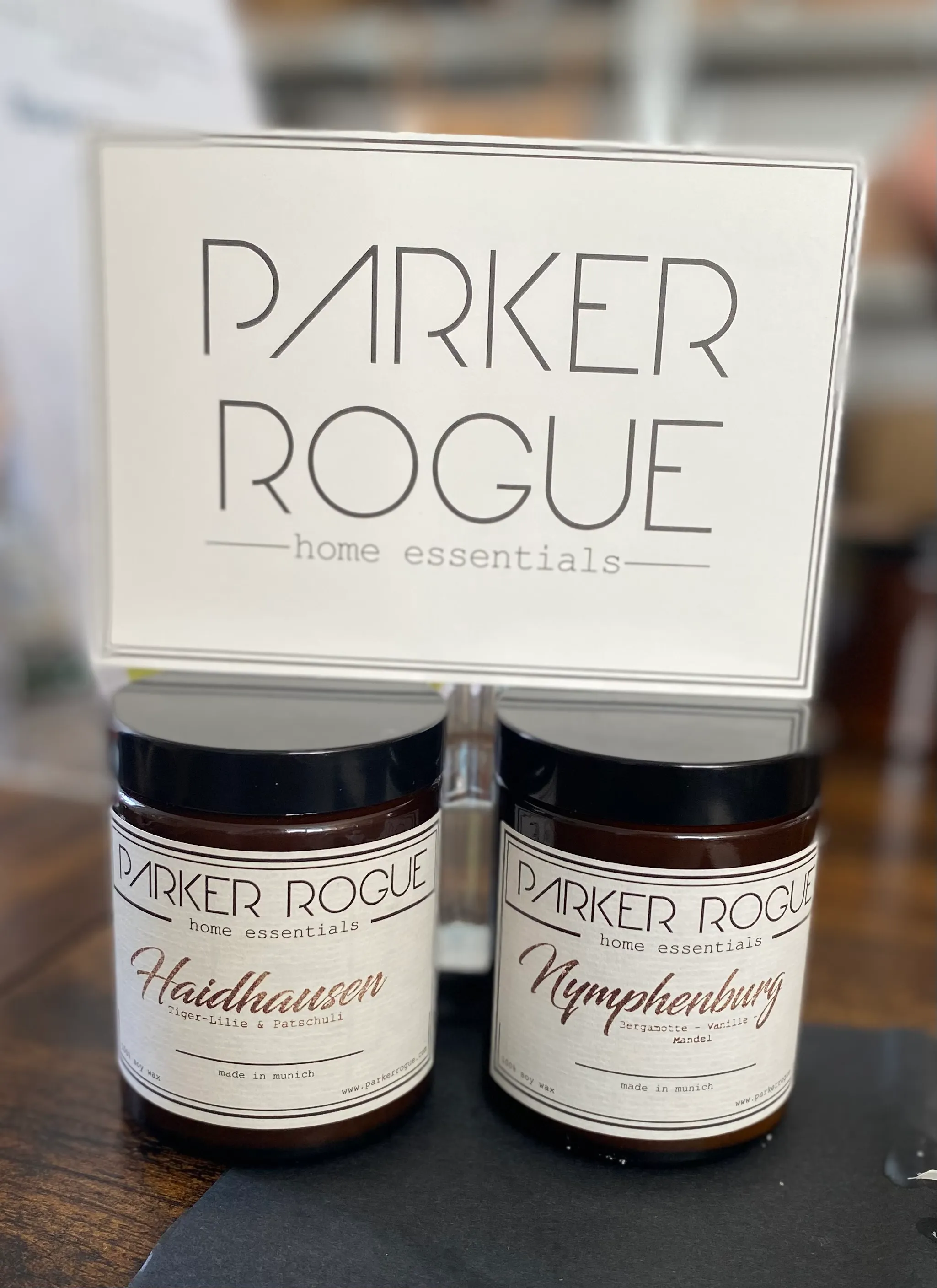 Candles labeled Parker Rogue on wooden table.