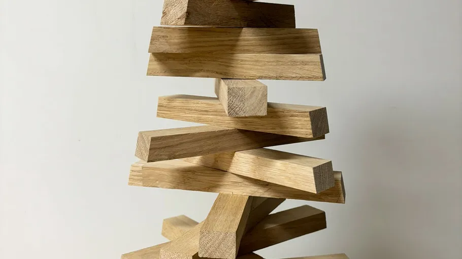 Stacked wooden blocks balancing precariously indoors.
