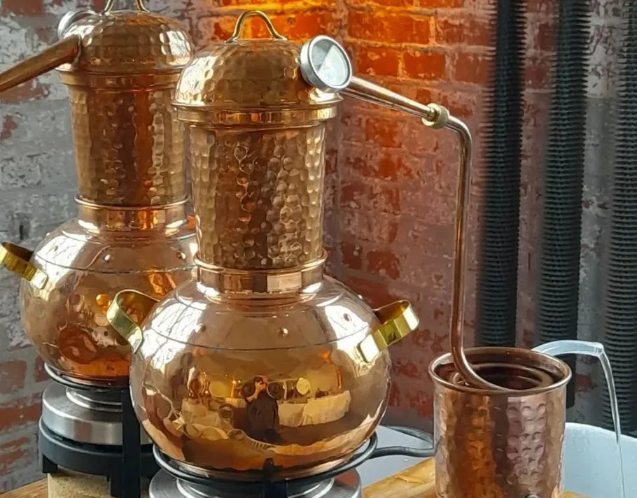Copper alembic stills in a brick-walled distillery.
