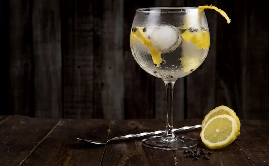 Cocktail glass with lemon slice on wooden table.