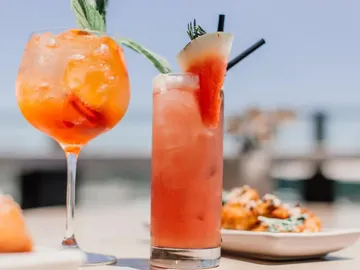 Two cocktails are on a table, summery atmosphere.