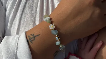 Perlenarmband am Handgelenk mit Blumenmotiv.