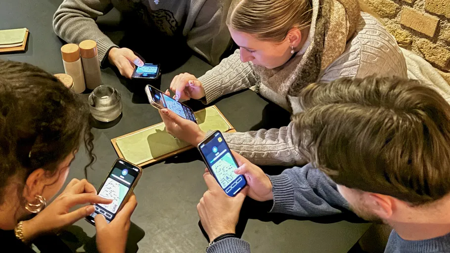 Leute spielen ein Handyspiel am Tisch.