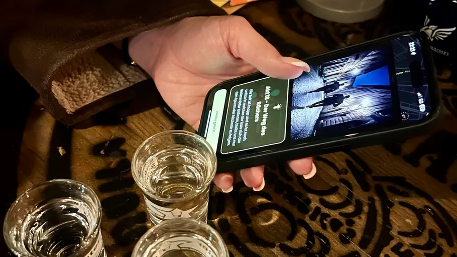 Hand holding phone displaying images, next to glasses.