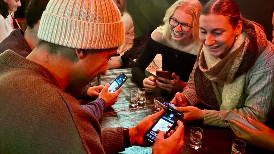 Gruppe von Freunden lächelt mit Smartphones drinnen.