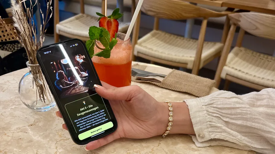 Person hält Handy mit App im Café.